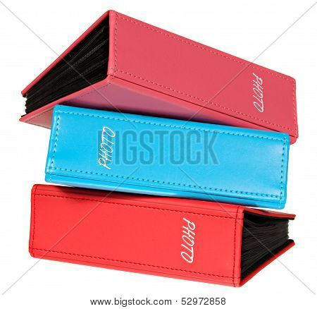 Three photograph albums of pink, red and blue color.