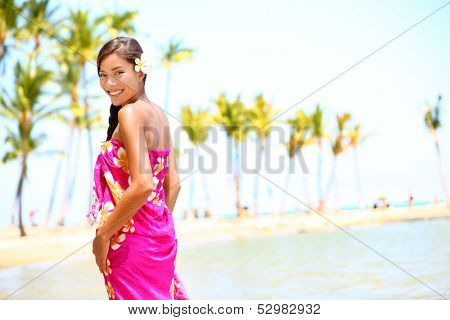 Beach travel - woman smiling happy on Hawaii. Girl in sarong cheerful on sunny hawaiian palm tree beach on holiday resort vacation. Big Island, Hawaii, USA. Multicultural Asian Caucasian female model.