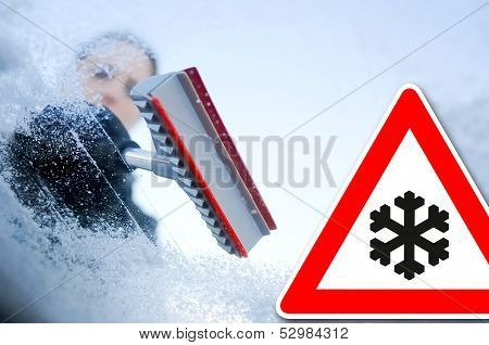 winter driving - scraping ice from a windshield