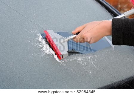 winter driving - scraping ice from a windshield