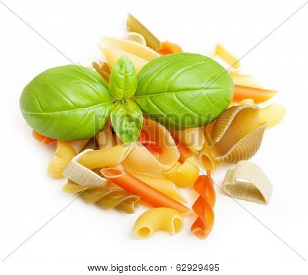 Heap of different type of pasta and basil leaf on white background