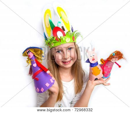 Little girl demonstrating her cruft work Easter bonnet, paper dolls and reindeer