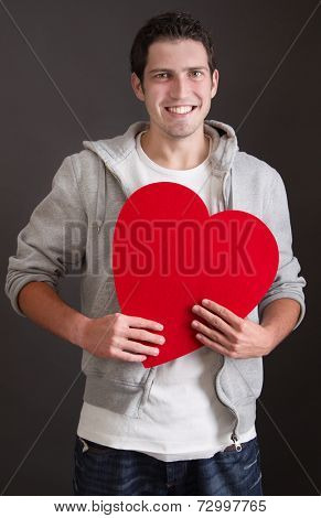 Three-quarter length of young Caucasian man with huge heart in his hands. 