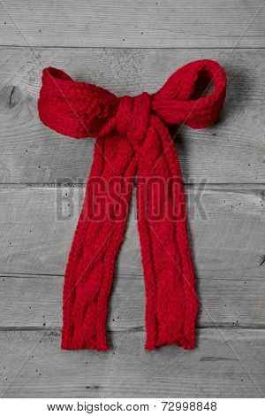 Red knitted bow for a present on grey wooden background - greeting card for christmas or birthday