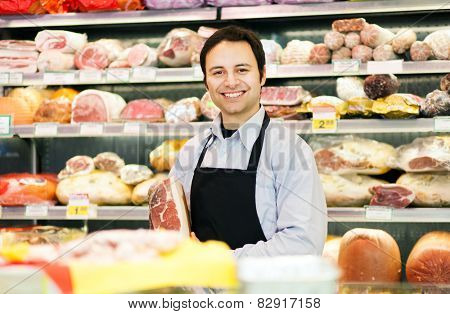 Storekeeper smiling in his grocery store holding a speck