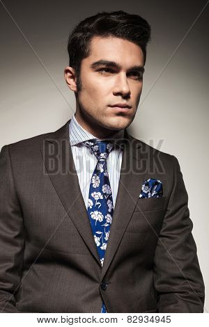 Close up picture of a young business lookin away from the camera, on grey studio background.