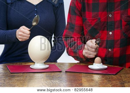 Woman And Man With Spoons Eating Hen And Ostrich Eggs