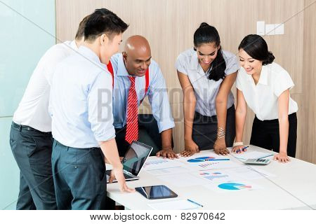 Asian business startup team in meeting discussing plan, figures, and ideas