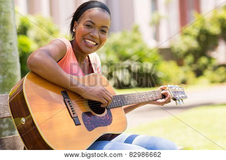 beautiful african american woman playing guitar outdoors