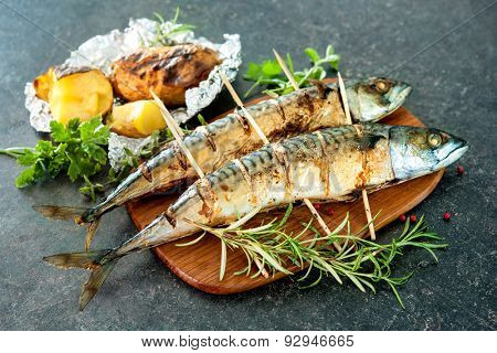 Grilled mackerel fish with baked potatoes on stone background