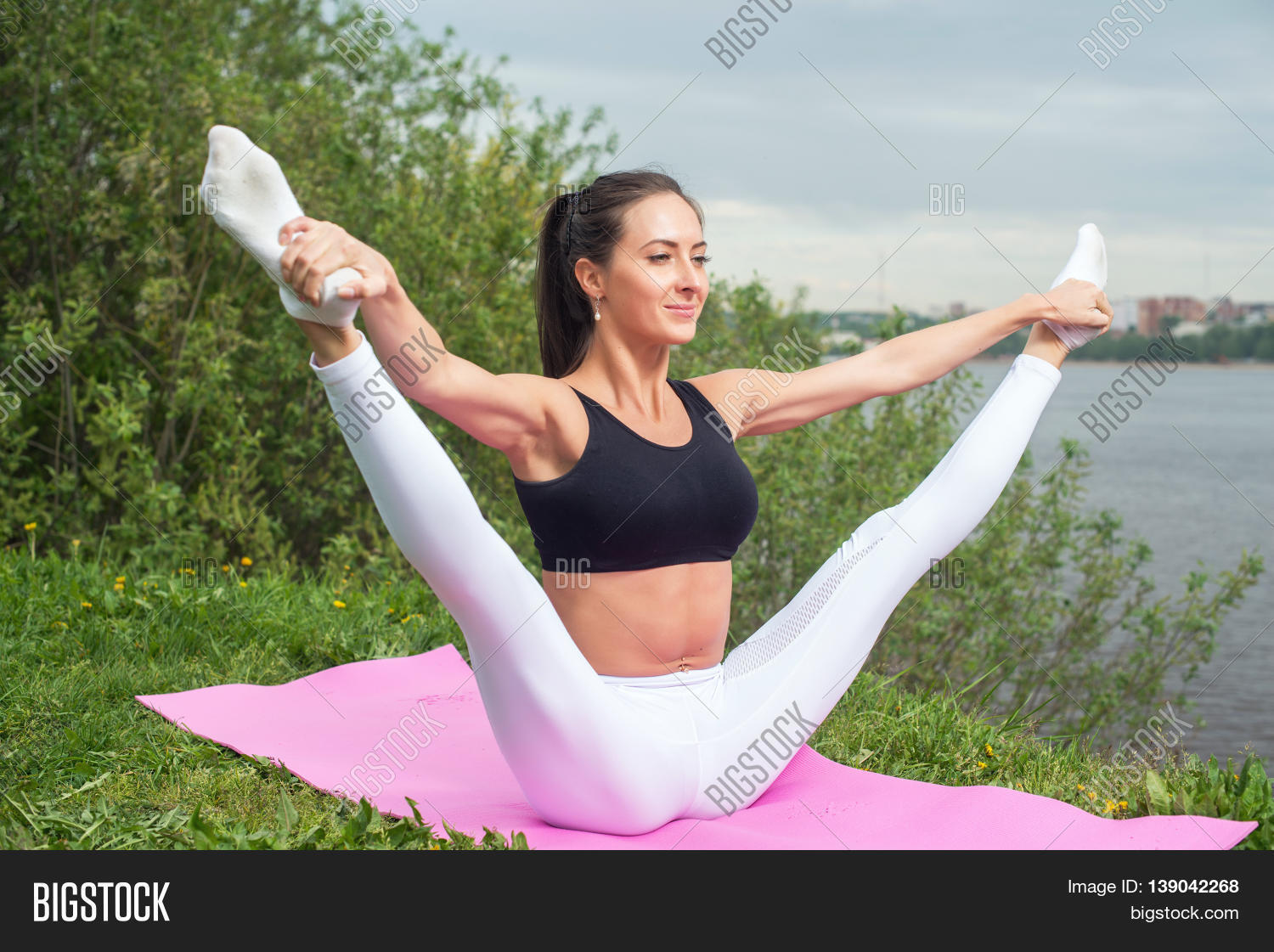 Full body woman in activewear holding leg on trapeze and doing