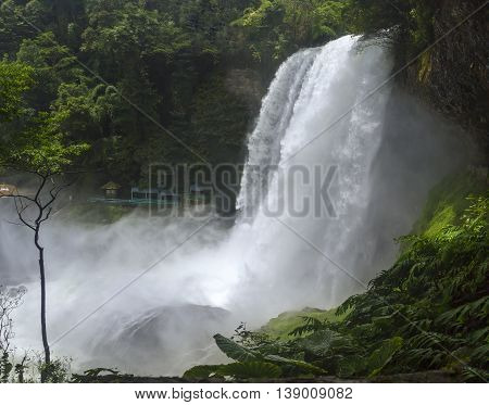 Dambri waterfall on summer days with over seventy meters high with high pouring down valley created a bridge crossing fog beauty fades when flying in conserving native forests in Lam Dong, Vietnam