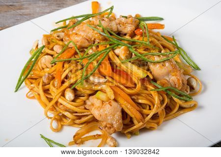 Thai fried noodles with chicken served on a white plate