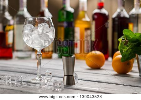 Bar jigger and wineglass. Glass full of ice cubes. Order whatever you want. Bartender's workplace in restaurant.