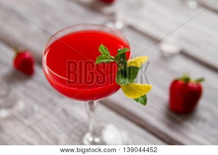 Bright red beverage in glass. Small branch of mint. Festive drink with alcohol. Freshly made clover club.