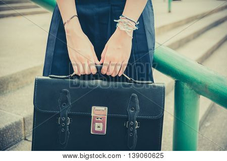 Body and hands of cute Asian Thai high schoolgirls student in school uniform holding black leather bag in education fashion in retro vintage childhood concept