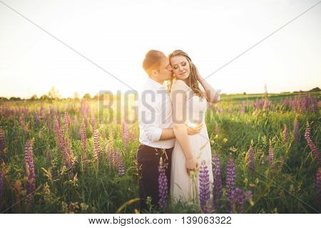 Beautiful wedding couple, love on the sunset. Fielf with flowers.