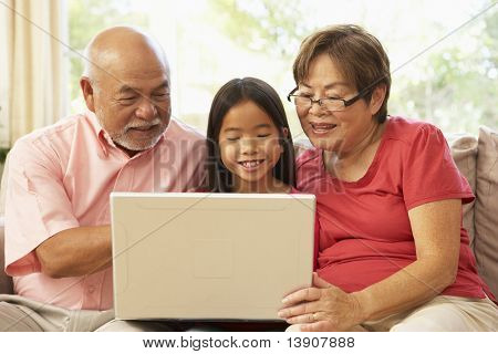 祖父母と自宅でラップトップ コンピューターを使用しての Grandaughter