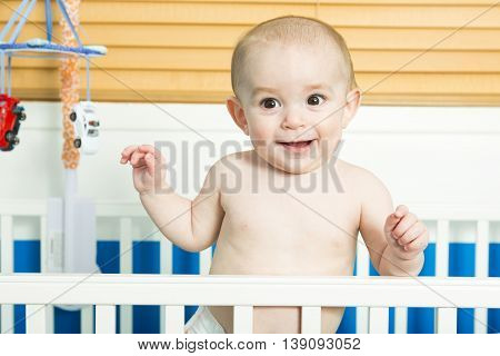 A baby in white crib Nursery interior and bedding for kid