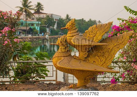 Two Gold Sculptures Of Birds. One Bird Sits On The Other. Bago In Myanmar. Burma.
