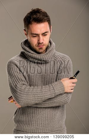 The man with his head down in anxious mood holding a smoking pipe and a match in hand. Studio, gray background.