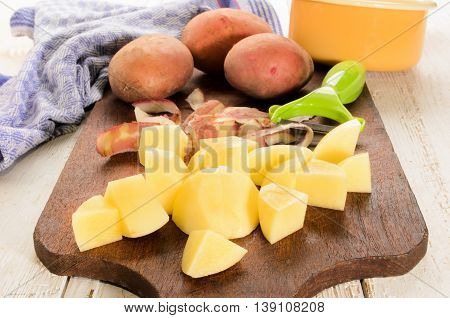 peeled and prepared potatoes in small cube on wooden board