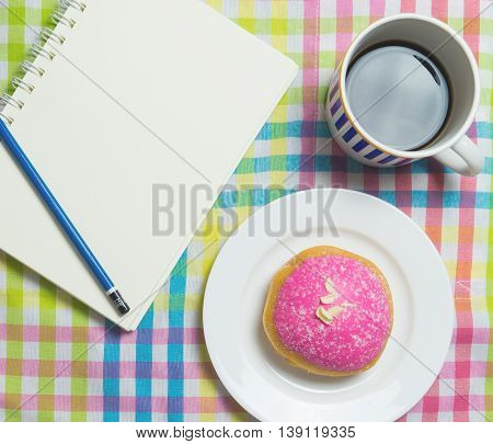 Strawberry Donut with Hot black coffee with notebook copy space.