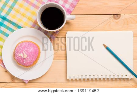 Strawberry Donut with Hot black coffee with notebook copy space.