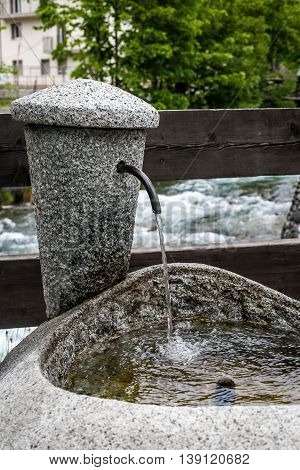 water flows in a stone standpipe near a river