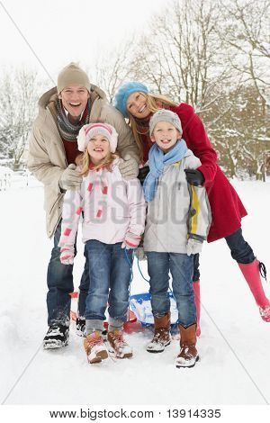 Familie trekken slee door besneeuwde landschap