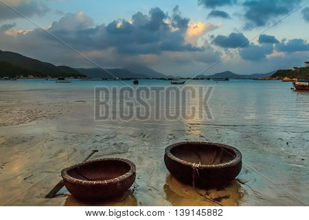 Traditional Vietnamese fishing boats on the shore at low tide in a bay in Vietnam at twilight