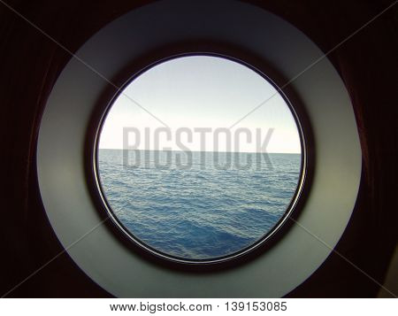 Porthole into the open sea from a cruise ship.