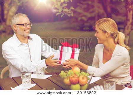 family, happiness, generation, home and people concept - happy family with gift box having holiday dinner outdoors