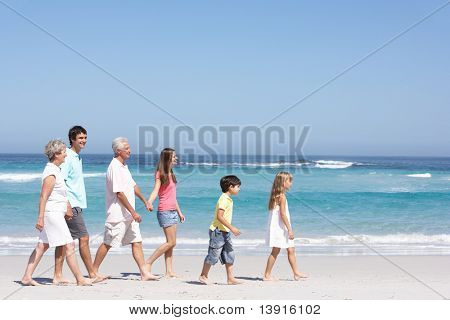 Tre Generation familie gåture langs sandstrand