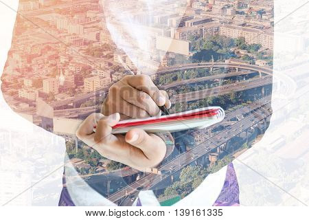 Double exposure of businesswoman  writing the word on a notebook on cityscape background.