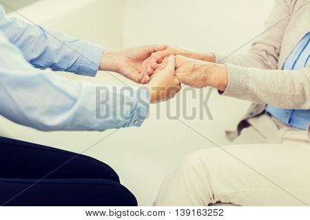 people, age, family, care and support concept - close up of senior and young woman  holding hands
