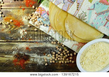 Colorful Indian food - papadum chickpea gram flour and spices on textured wooden table top