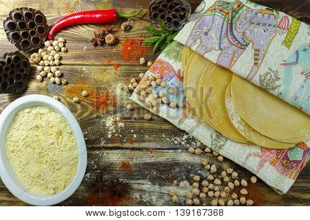 Colorful Indian food - papadum chickpea gram flour and spices on textured wooden table top