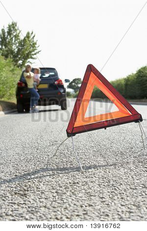 Mor og datter brudt ned på landevej med Hazard advarselsskilt i forgrunden