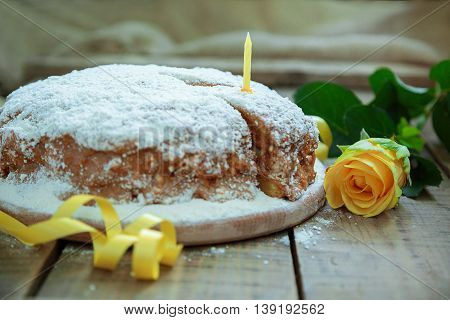 Birthday party. Birthday in yellow style. Home cake. Piece of cake with a candle on a wooden table yellow rose and ribbon