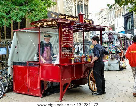 CAMBRIDGE UNITED KINGDOM - JULY 18 2011: Student talking to a vendor at a traditional hot dog stand.