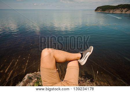 Male legs over the lake and rocks