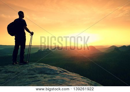 Man With Tourist Poles In Hand And Sporty Backpack Above Valley.