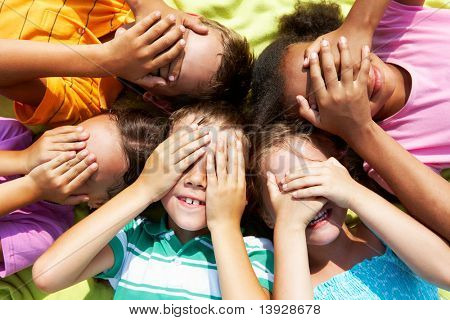 Portrait of happy preschoolers lying and closing eyes by hands