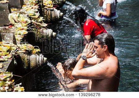 BALI, INDONESIA, 8 April 2016: Praying in Tirta Empul. Tirta Empul temple is a Hindu Balinese water temple located near the town of Tampaksiring, Bali, Indonesia. The temple compound consists of a petirtaan or bathing structure, famous for its holy spring