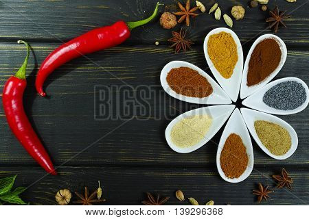 Colorful variety of Indian spices on black wooden table top