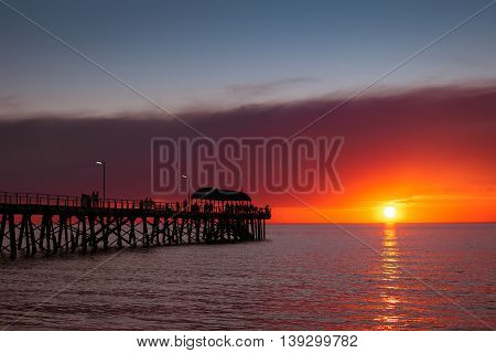 People walking on the Henley Beach Jetty at sunset South Australia. Color-toning applied