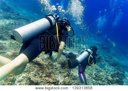 Two divers scuba diving in tropical sea at reef