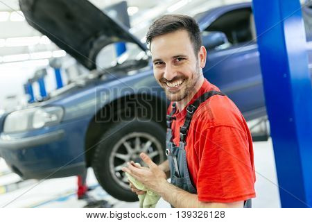Car mechanic fixing a car in garage at dealership