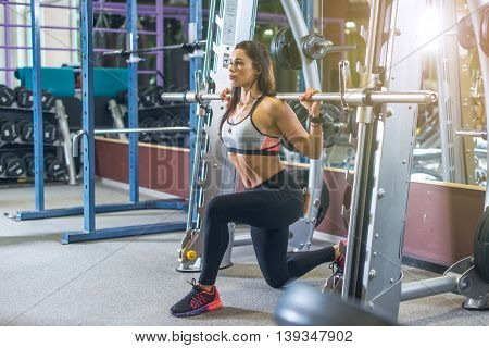 Fit girl doing lunges with the smith machine.